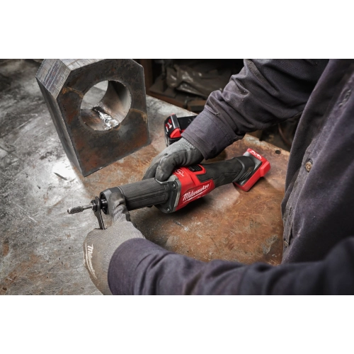 Pracownik obrabia Milwaukee M18 FDGROVB element stalowy na stole warsztatowym