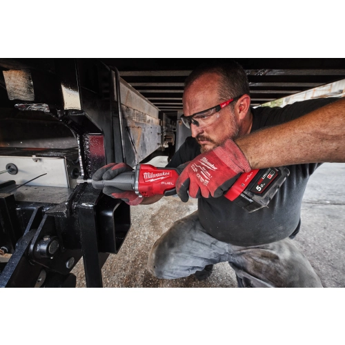 Pracownik szlifuje Milwaukee M18 FDGROVPDB konstrukcję naczepy
