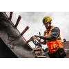 Dekarz w kasku tnie Milwaukee M12 FCS442 łatę na dachu z membraną
