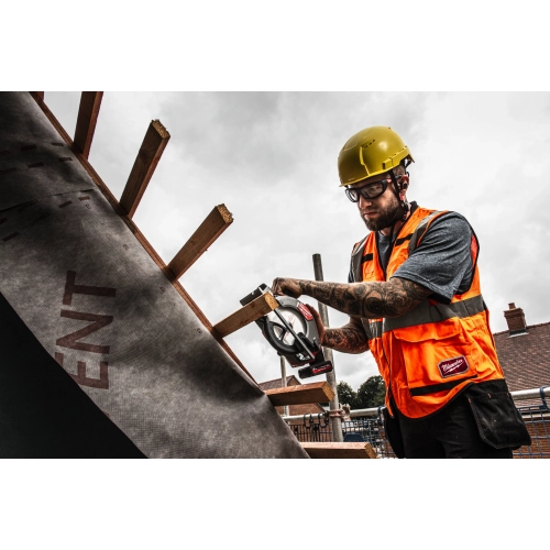 Dekarz w kasku tnie Milwaukee M12 FCS442 łatę na dachu z membraną