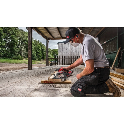 Mężczyzna tnie Milwaukee M18 FCS552 deski tarasowe na zewnątrz