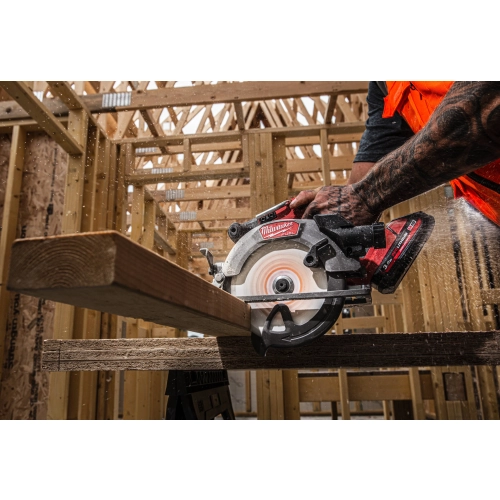 Pracownik tnie Milwaukee M18 FCS552 deskę na kozłach, trociny lecą na bok