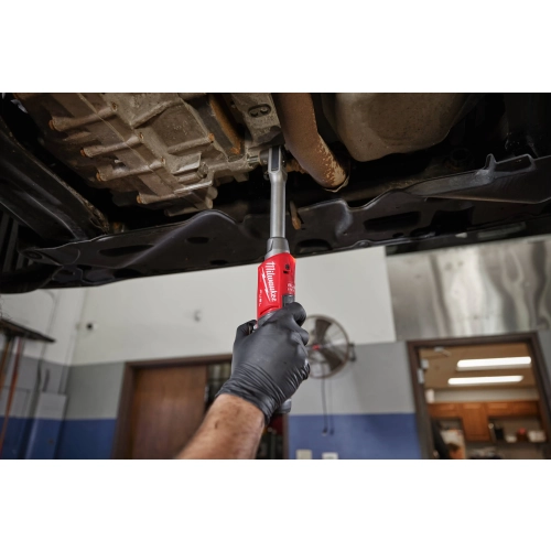 Mechanik pod ciężarówką kręci Milwaukee M12 FPTR nakrętkę w ramie