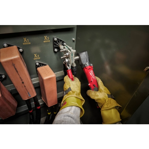 Elektryk w rękawicach dielektrycznych dokręca Milwaukee M12 FRAIWF38 śruby szyn w rozdzielnicy