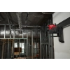 Laser Milwaukee M12 CLL4P zamocowany wysoko na ścianie przy instalacjach