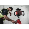 Monter ustawia niwelator Milwaukee M18 RLOHVG300 na statywie przy ścianie