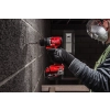 Pracownik w masce wierci Milwaukee M18 BLPDRC w ścianie z bloczków