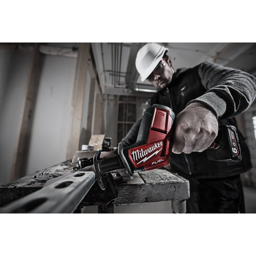 Milwaukee M12 CHZ z bliska tnie profil stalowy na stole, kołnierz FIXTEC widoczny