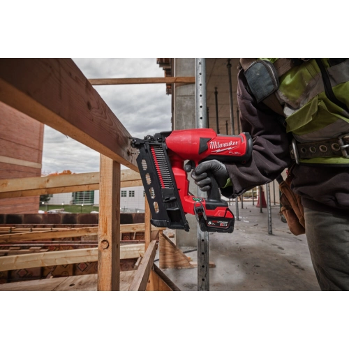 Milwaukee M18 FDN wbija gwóźdź w belkę przy rusztowaniu