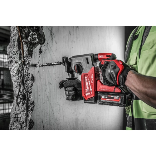 Milwaukee M18 ONEFH wierci wiertłem SDS-Plus otwór w betonowej ścianie, ręka na rękojeści bocznej