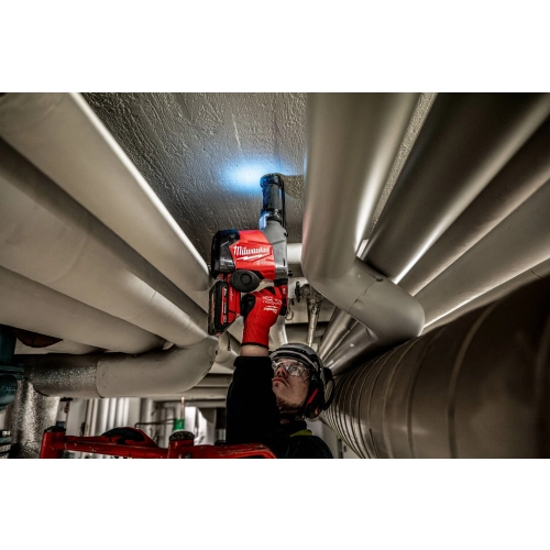 Milwaukee M18 FHAFOH16 z włączoną diodą LED wierci nad głową między rurami instalacji