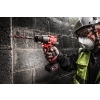 Pracownik w masce wierci Milwaukee M12 FPD2 wiertłem do betonu w ścianie z bloczków