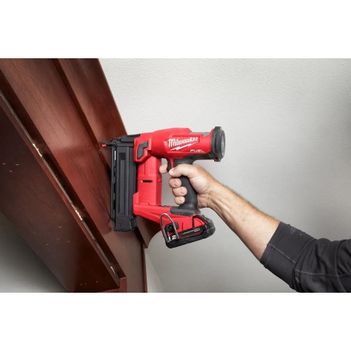 Milwaukee M18 FN18GS mocuje ciemną drewnianą listwę do ściany