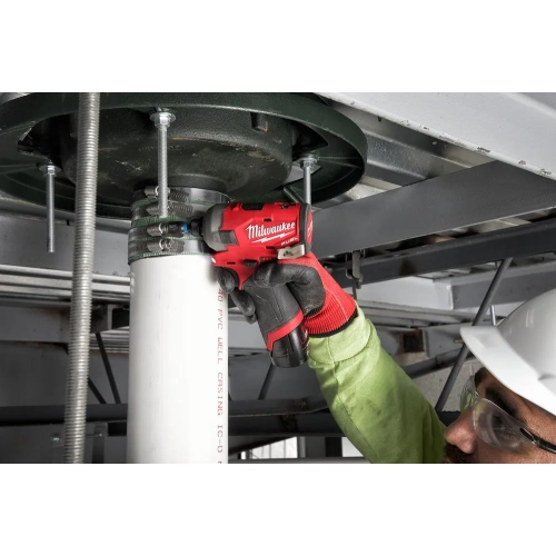 Pracownik dokręca Milwaukee M12 FQID uchwyt rury pod stropem