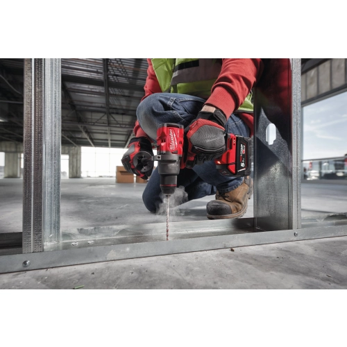 Milwaukee M18 FDD3 wierci w stalowym profilu leżącym na posadzce