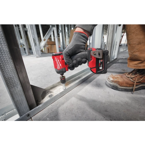 Milwaukee M18 FID3 z nasadką dokręca śrubę w stalowej szynie przy podłodze