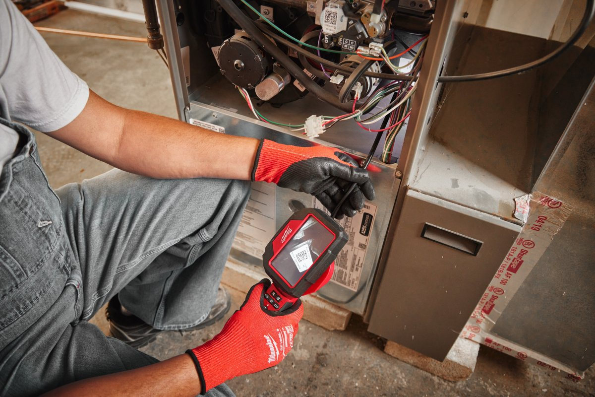 Serwisant ogląda wnętrze pieca kamerą inspekcyjną Milwaukee M12 360IC z obrotowym ekranem