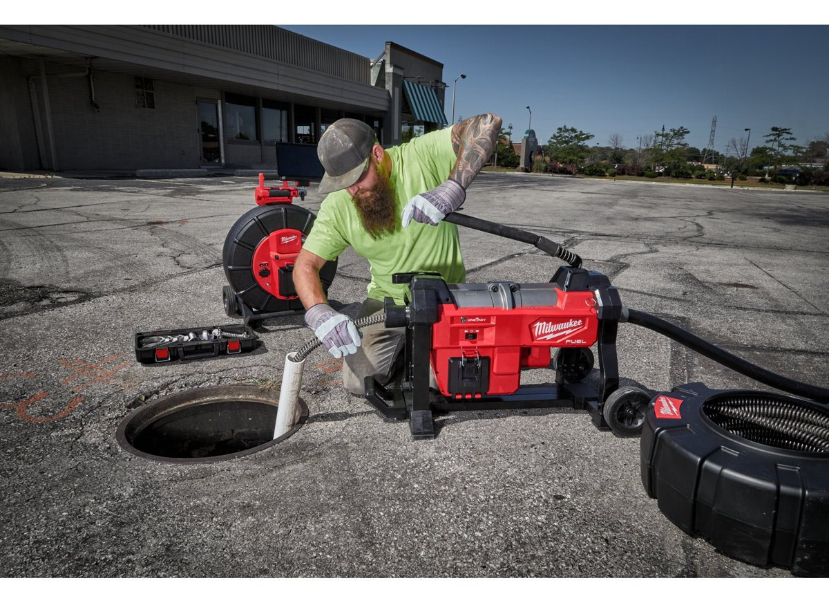 Hydraulik wprowadza popychacz kamery Milwaukee M18 SIC60 HDR do studzienki kanalizacyjnej