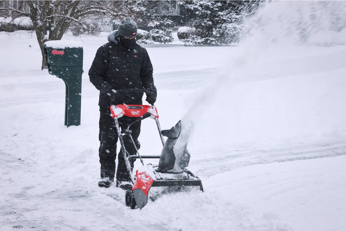 Mężczyzna odśnieża dojście do skrzynki na listy odśnieżarką Milwaukee M18 FUEL F2SSBL