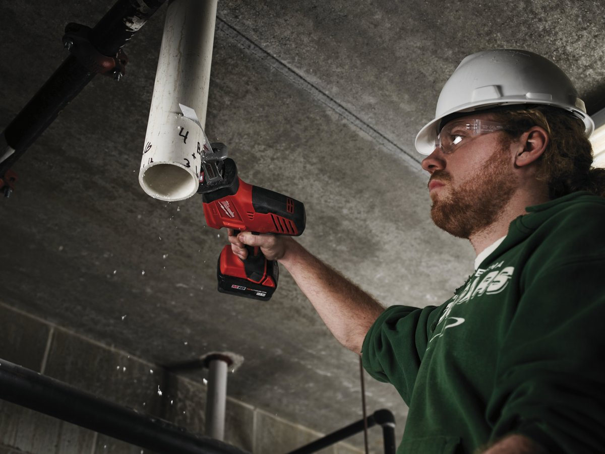 Instalator tnie rurę PCV pod sufitem kompaktową piłą szablastą Milwaukee C18 HZ