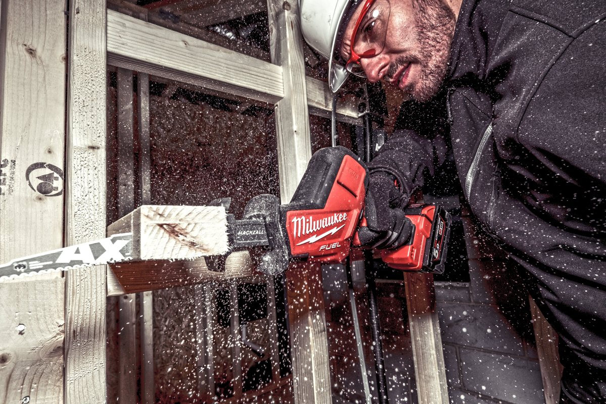 Robotnik wycina ościeżnicę okna kompaktową piłą szablastą Milwaukee M18 FUEL HACKZALL z brzeszczotem AX