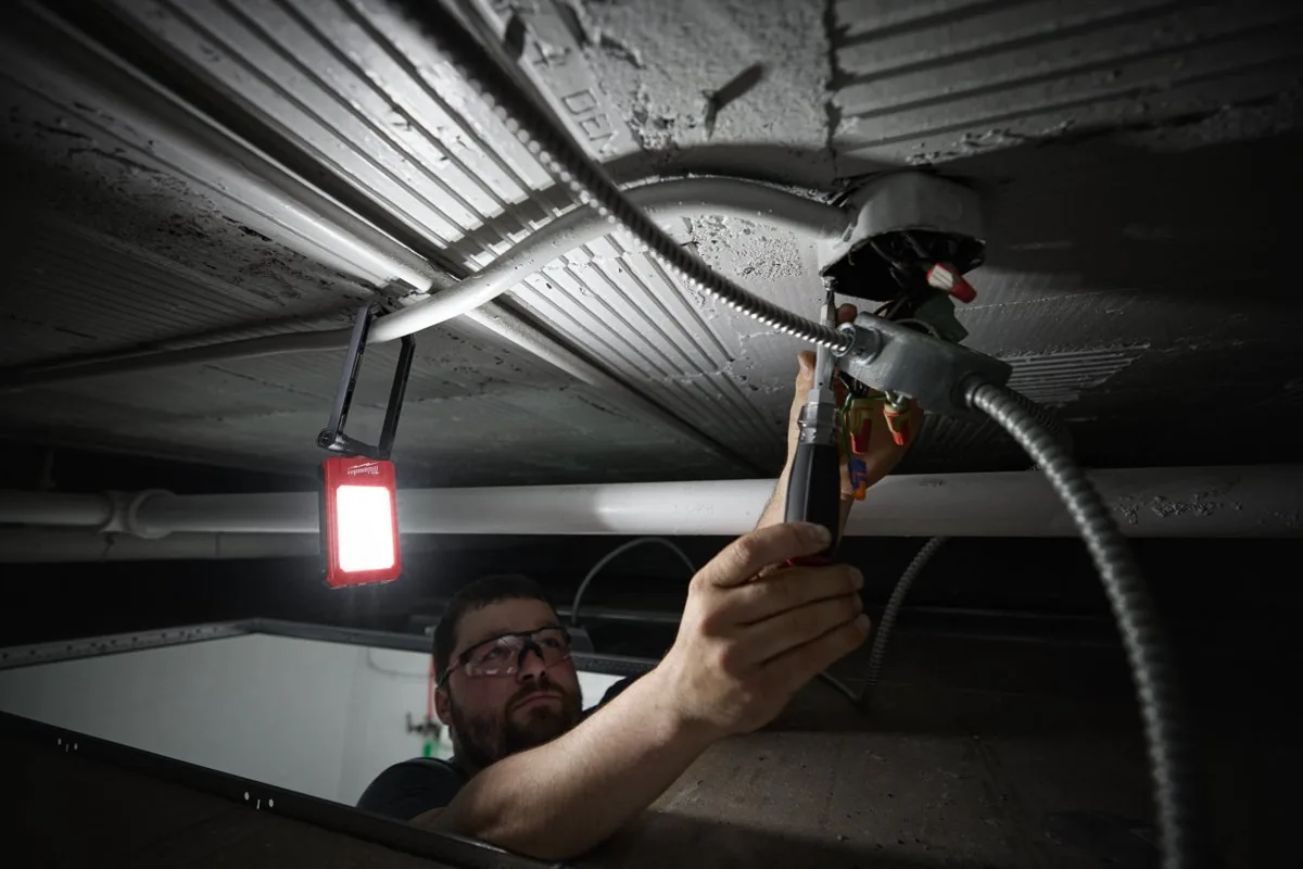 Elektryk pracuje nad głową, reflektor IR FFL zawieszony na instalacji