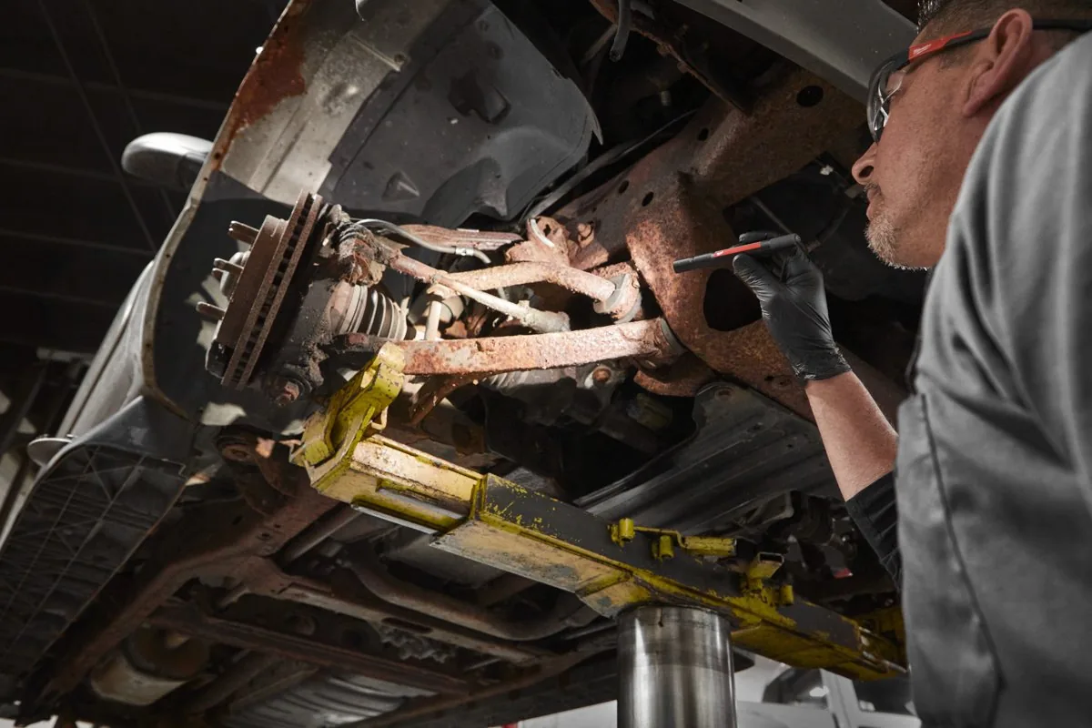 Mechanik oświetla zawieszenie samochodu latarką IR PL250