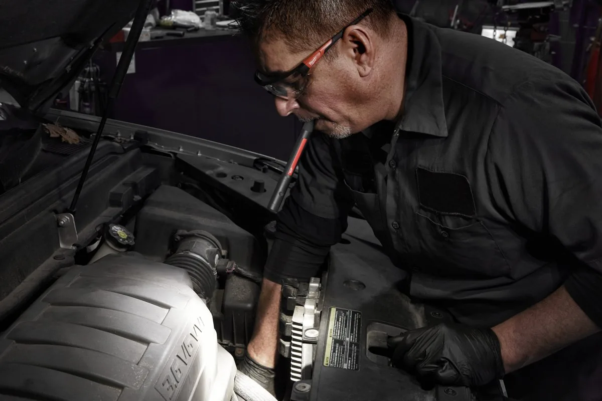 Mechanik pracuje w komorze silnika z latarką IR PL250 w zębach