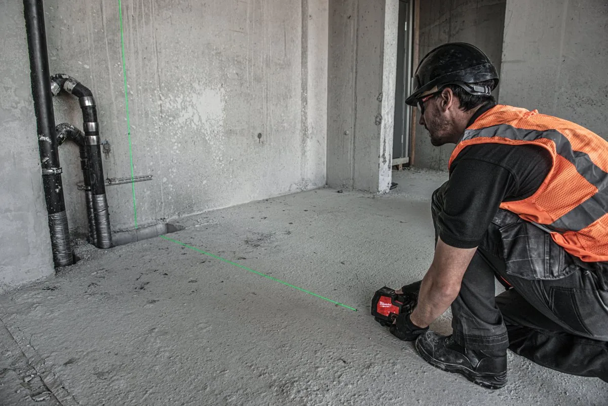 Monter układa laser L4 CLL przy ścianie z instalacjami