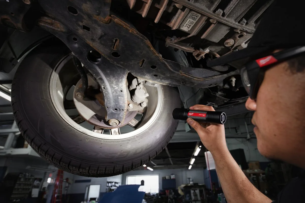 Mechanik oświetla podwozie samochodu latarką L4 FL2000