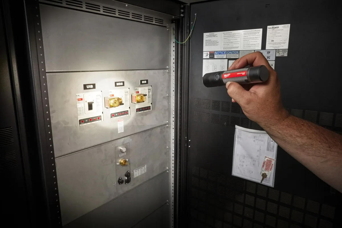 Elektryk sprawdza aparaturę w szafie z latarką L4 FMLED