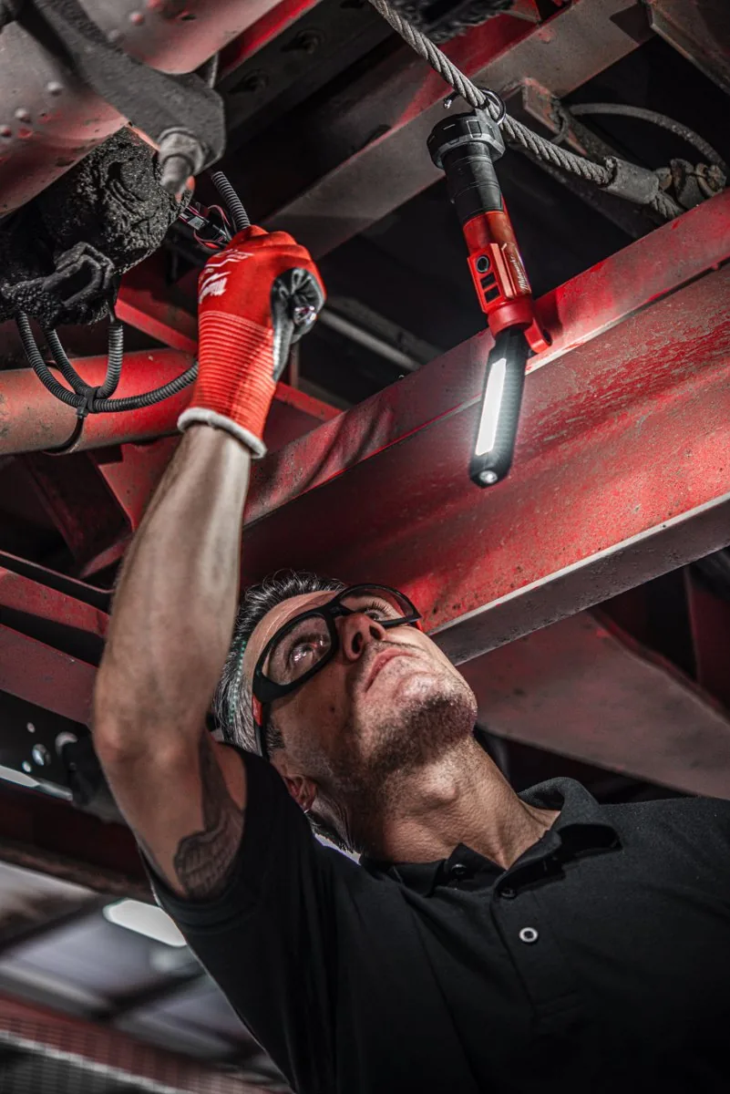 Mechanik oświetla podwozie latarką L4 SL550 zawieszoną na haku