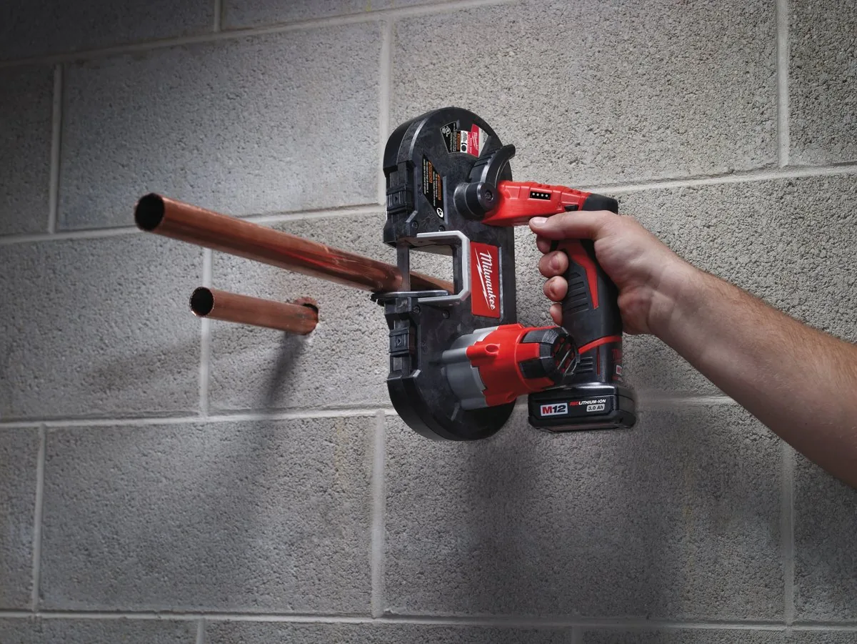 Instalator tnie rurę miedzianą przy ścianie piłą M12 BS