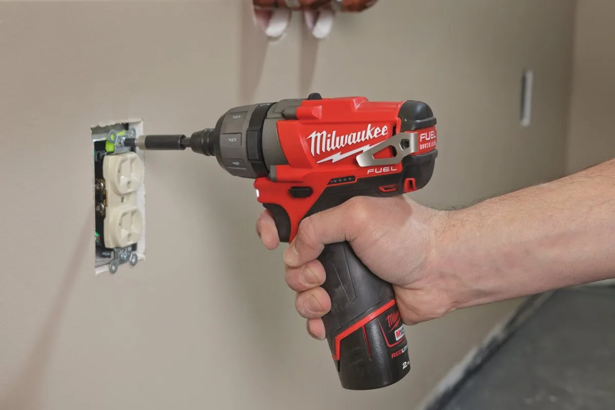Kompaktowa wkrętarka MILWAUKEE M12 z bitem przykręca gniazdko elektryczne w ścianie
