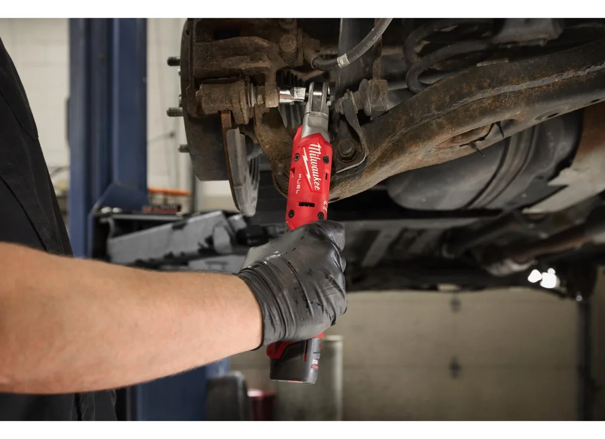 Mechanik w rękawicach odkręca grzechotką akumulatorową MILWAUKEE śrubę zacisku hamulcowego