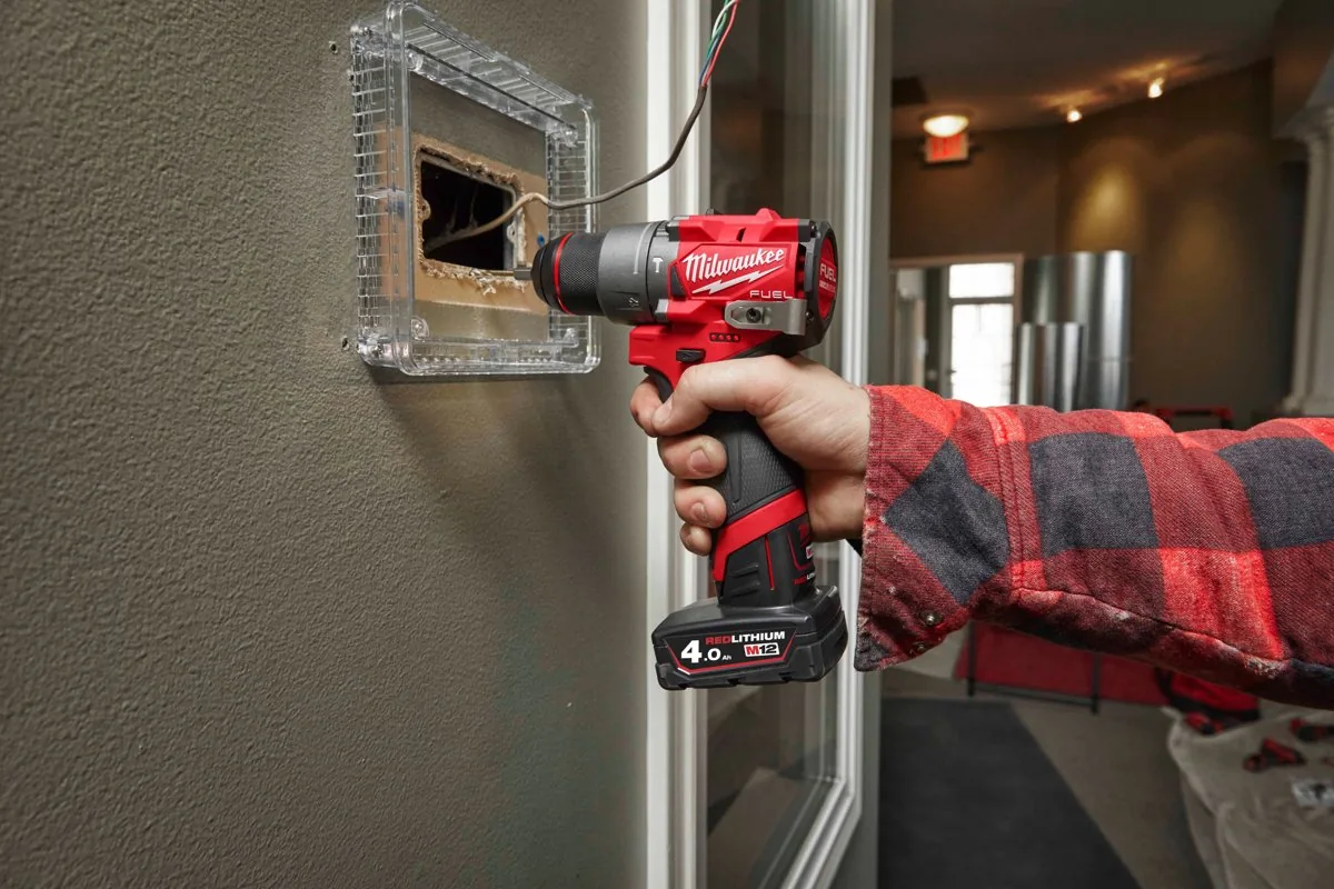 Kompaktowa wiertarko-wkrętarka MILWAUKEE wkręca wkręt przy puszce instalacyjnej w ścianie