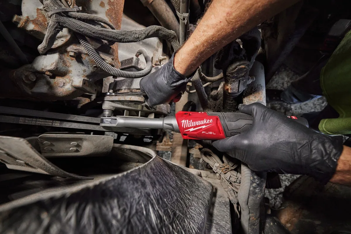 Mechanik w rękawicach kręci M12 FPTR nakrętkę w komorze silnika