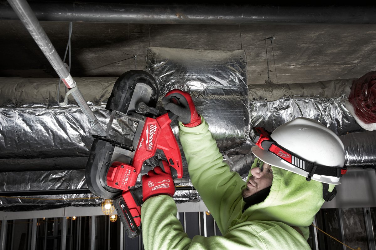 Instalator w kasku tnie M18 FBS85 pręt nad głową przy izolowanym kanale wentylacyjnym
