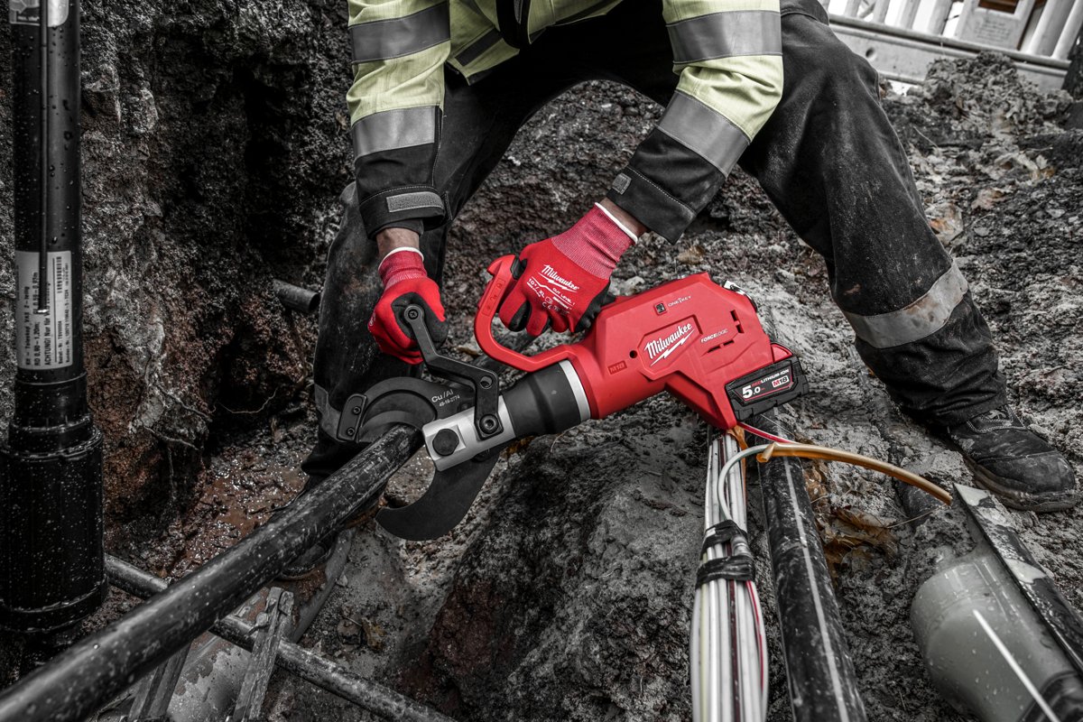 Monter zakłada hydrauliczne nożyce MILWAUKEE na gruby kabel w wykopie