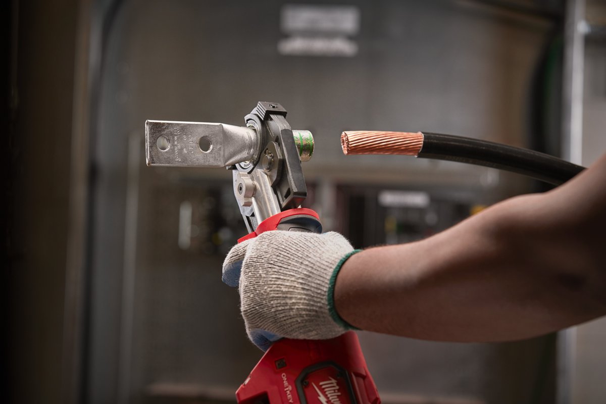 Elektryk zaciska końcówkę kablową na grubym przewodzie miedzianym zaciskarką hydrauliczną MILWAUKEE