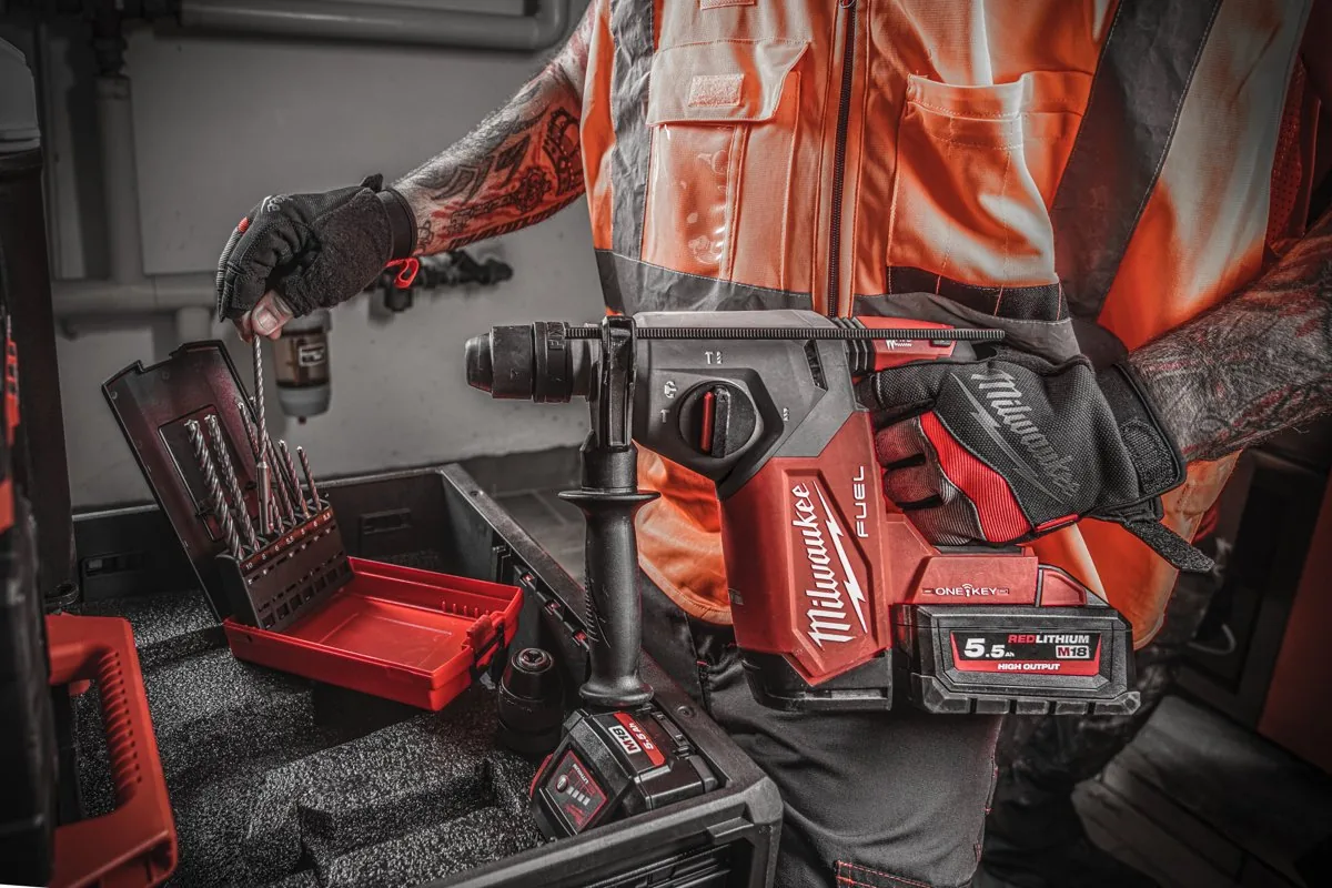 Pracownik trzyma zdjęty uchwyt FIXTEC nad M18 ONEFHX leżącą w walizce z wiertłami