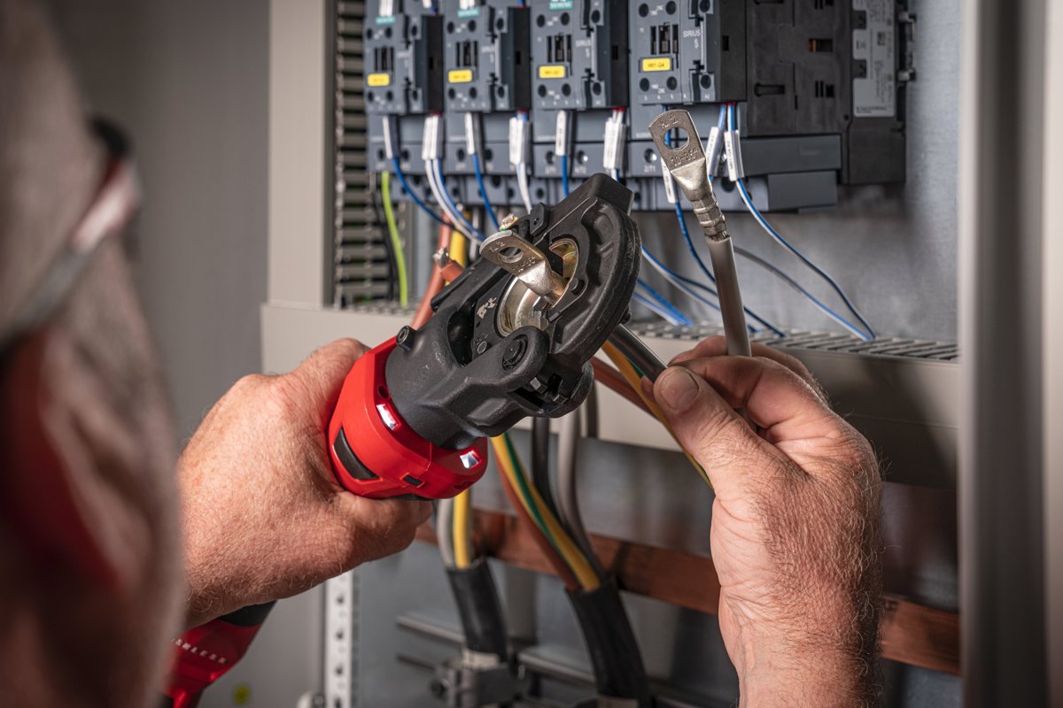Elektryk zaciska końcówkę przy aparaturze modułowej