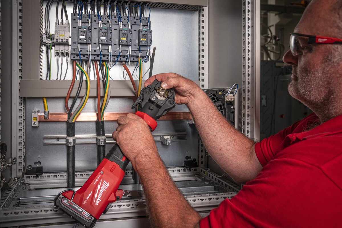 Elektryk zaciska końcówkę w rozdzielnicy zaciskarką M18 ONEHCCT60