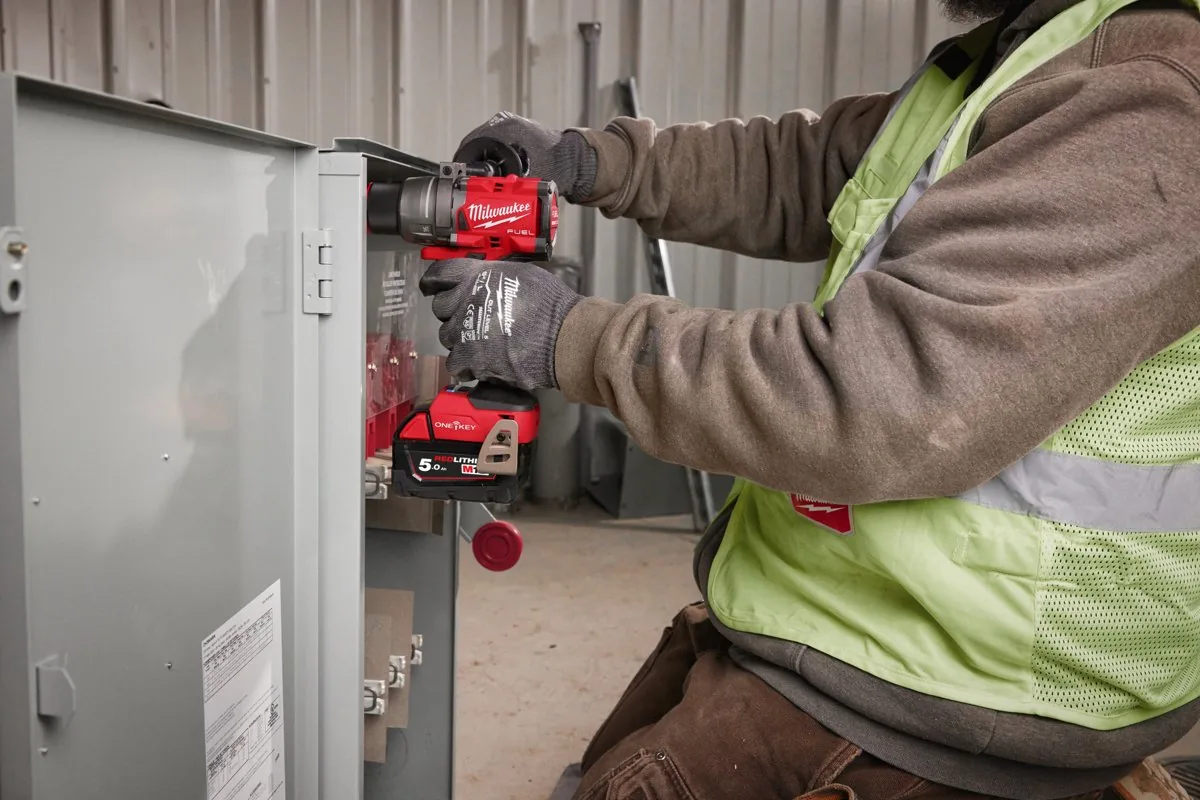 Elektryk wkręca M18 ONEPD3 w obudowie rozdzielni
