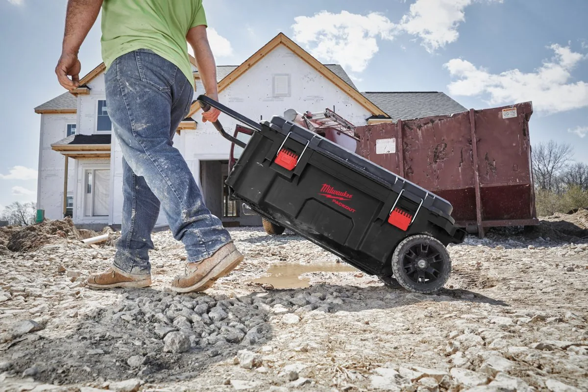 Pracownik ciągnie dużą skrzynię PACKOUT na kołach po terenie