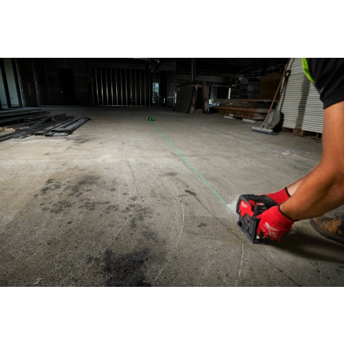 Monter wyznacza zieloną linię na posadzce laserem Milwaukee M12 CLLP