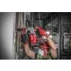 Pracownik w kasku wierci Milwaukee M18 BLHX nad głową przy nadprożu okna