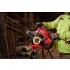 Pracownik tnie Milwaukee M18 FBS127DO rurę na stojaku w hali obok stosu rur