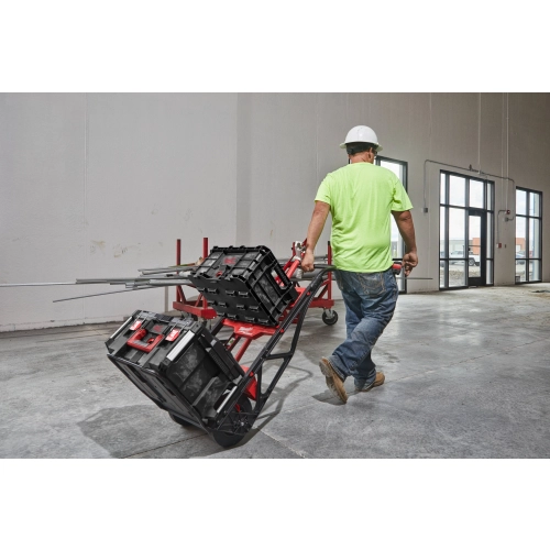 Wózek transportowy Milwaukee PACKOUT 180 kg – Pracownik przewozi skrzynie na wózku PACKOUT przez halę